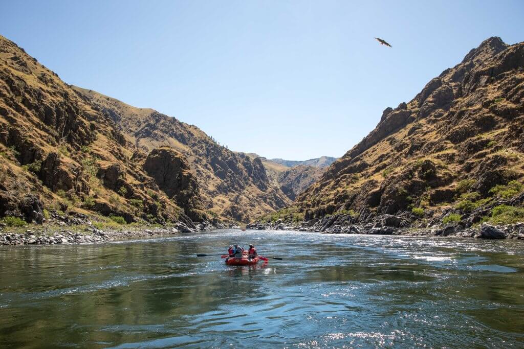 A group of people paddling a raft over rapids on the Payette River.
